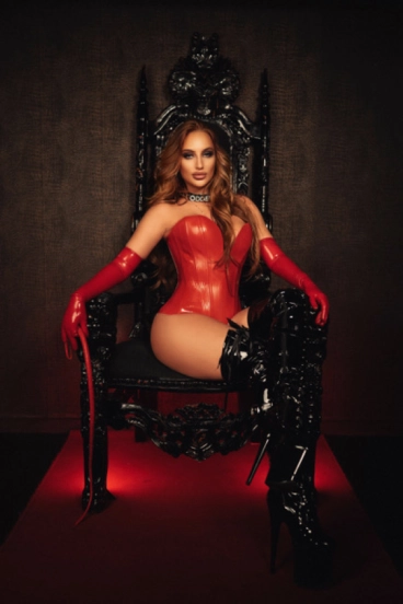 Mistress Shay sitting in a large black chair