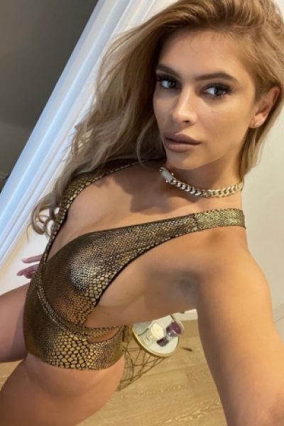 Blair standing in a gold scaled set of lingerie 