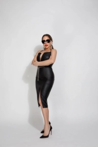 Full length photo of Juniper dressed in a black dress and wearing dark sunglasses 