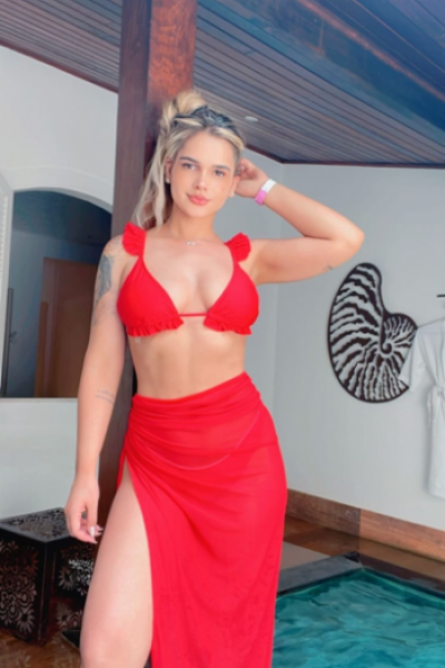 Versi is wearing a red bikini top and a sarong wrapped around her waist 