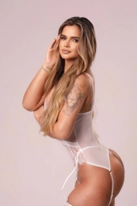 Veris is wearing a white lace body and is showing off her large arm tattoo in this picture 