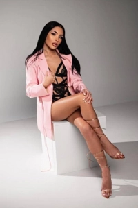 Beautiful London escort sitting on a white box with her legs crossed 