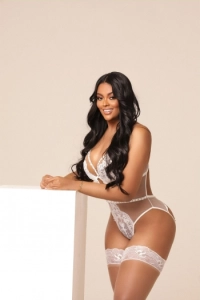 Leaning up against a white wall and white white lingerie is a very busty escort lady called Journee