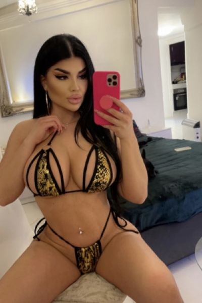 Sexy selfie of curvy escort Haifa sitting on the edge of her bed 