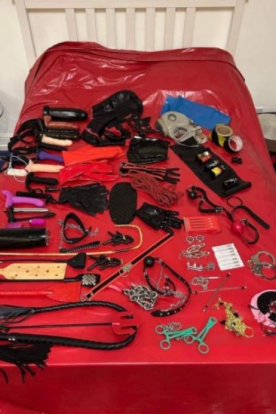 Mistress Phoenix is showing off her toys laid out on her bed 