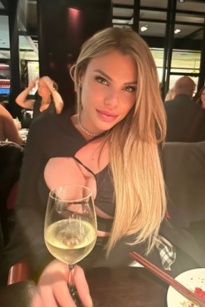 A very sexy blonde escort is enjoying a glass of wine 