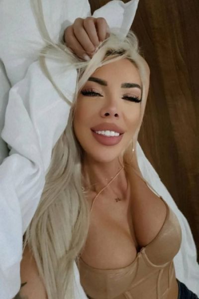 A selfie of sexy blonde escort Yasmin laying on her bed 