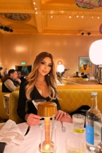 A sexy brunette TS escort sitting at a dinner table 