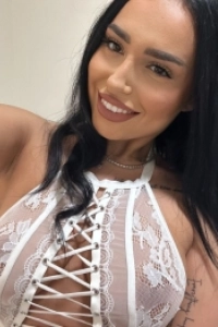 Close up of a brunette escort wearing a white lace see through top 