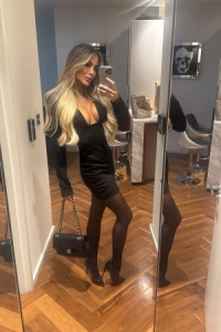 Slim busty high class Brazilian escort wearing a black dress 
