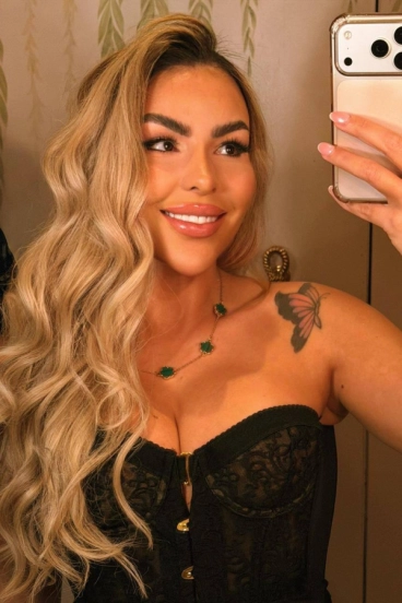 Brazilian escort Lainey taking a selfie wearing a low cut top 