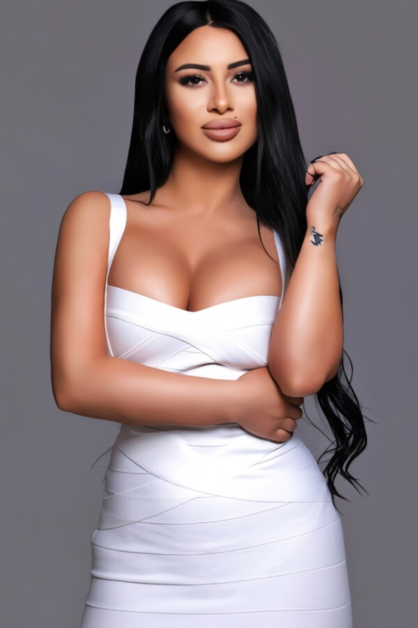 Elegant brunette busty London escort in white figure-hugging dress