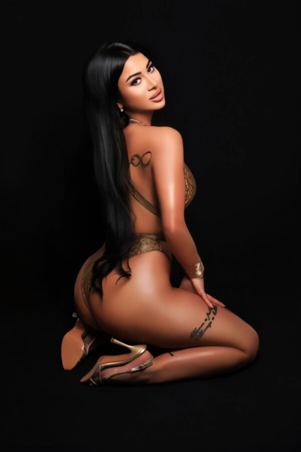 Glamorous brunette escort in gold swimsuit, kneeling pose