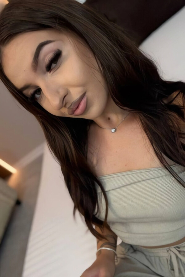 A beautiful brunette lady taking a picture of herself while sat down