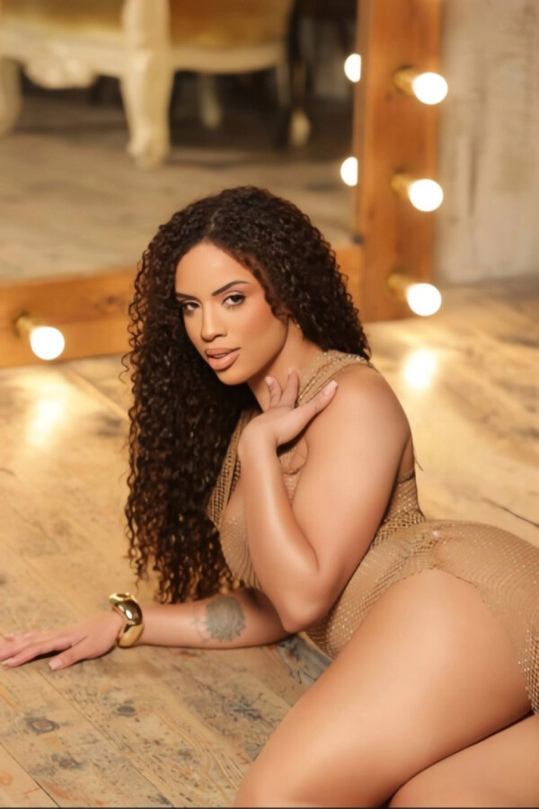 Tais curvy brunette London escort posing in golden mesh dress