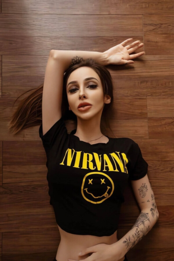 Rafaela lying on a wooden floor in a Nirvana crop top