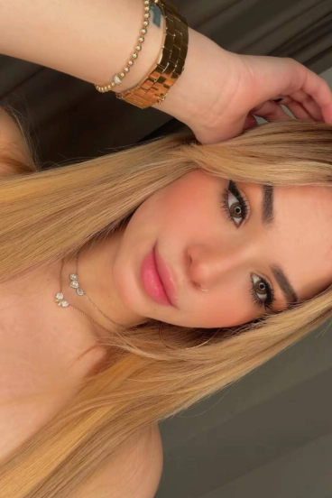 Close-up selfie of Joana with long blonde hair, brown eyes, nose ring and gold jewellery.
