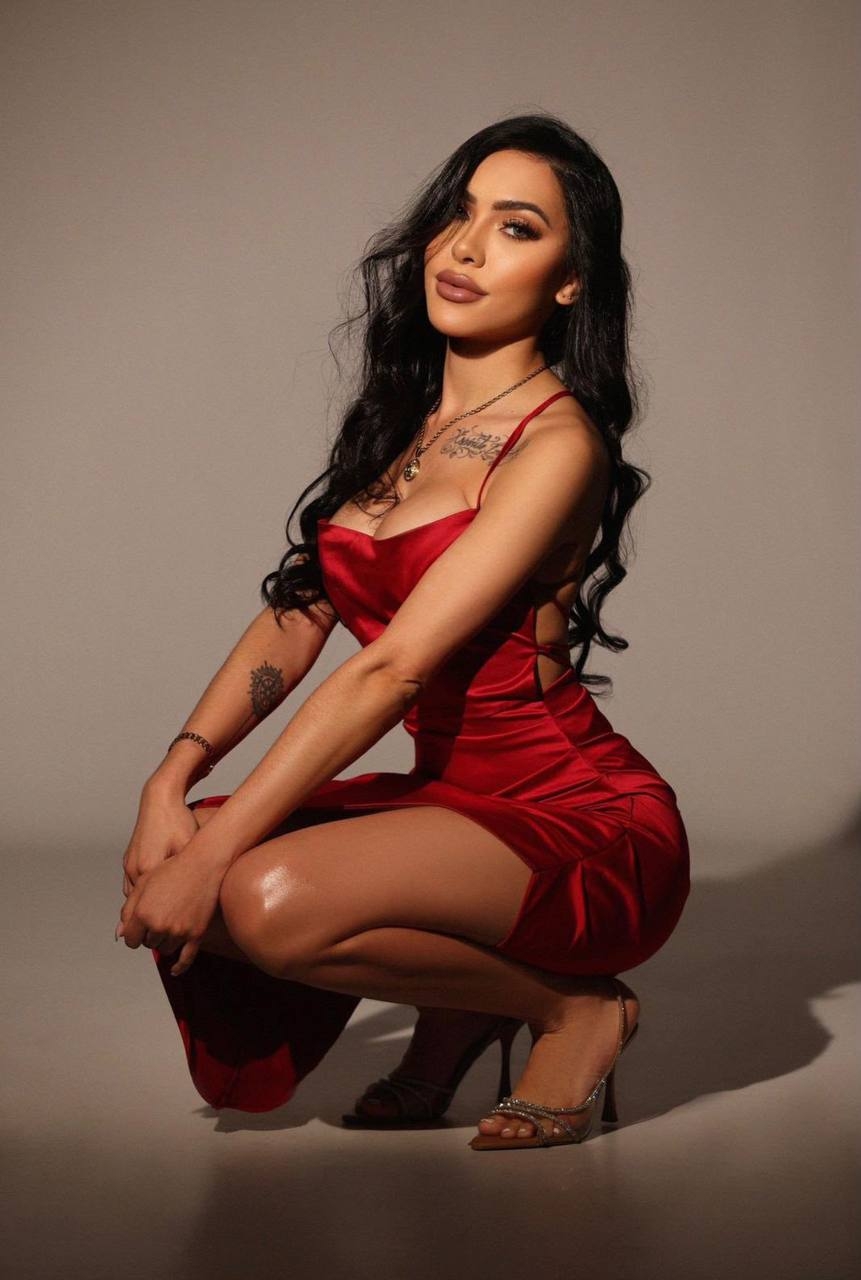 Trinny crouching in a red satin dress and silver heels during a studio shoot