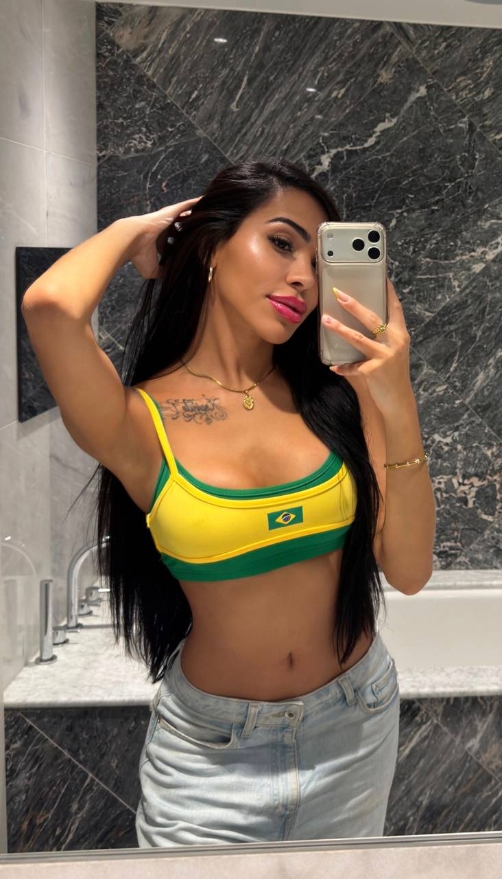 Trinny taking a bathroom mirror selfie in a yellow and green Brazil crop top