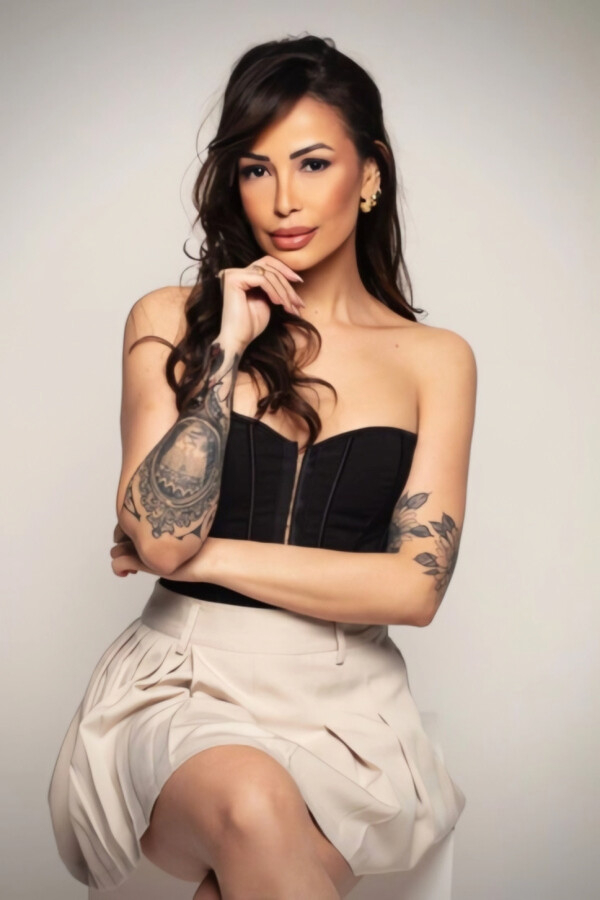 Elegant and sexy escort with a large tattoo on her arm