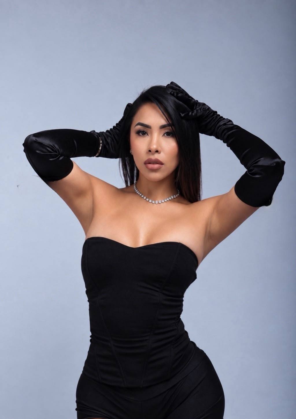Tori poses in a black strapless outfit with satin opera gloves and a sparkling necklace.