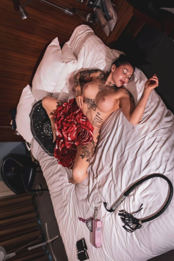 Tattooed naked lady laying on a large bed