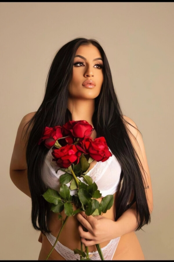 Beautiful brunette London escort with big lips holding some roses